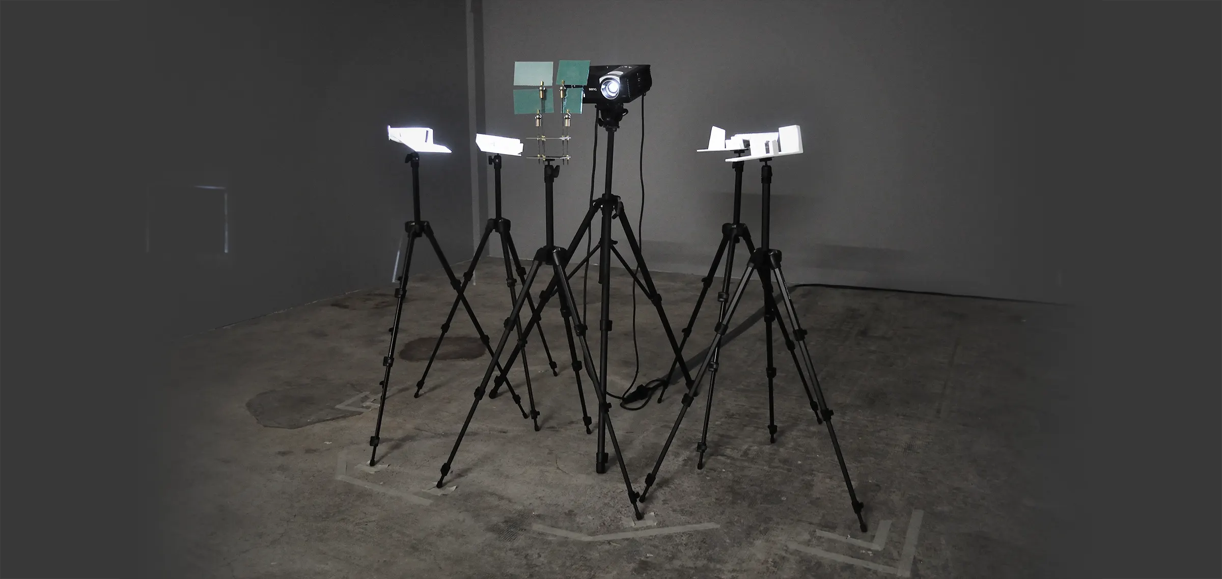 4 miniatures mounted on tripods. In their center a projector and another tripod with four small mirror to divide the light across all miniatures.