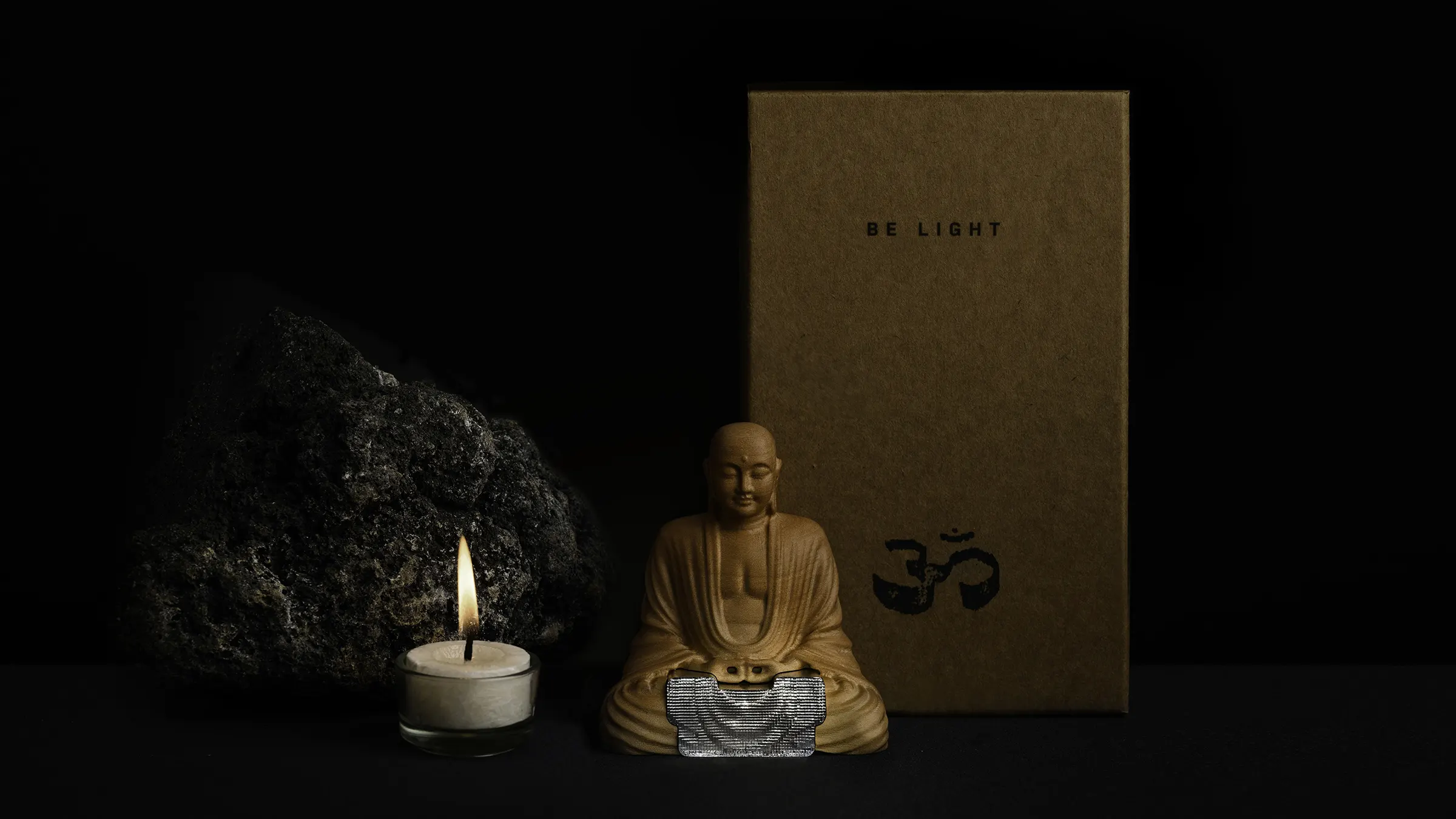 The Buddha figure and candle together with its packeing box and a stone.